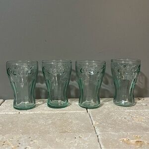 Four mini vintage Coca Cola glasses.